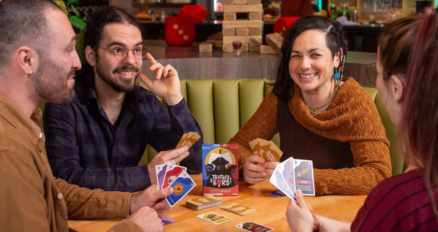 Vier Freunde lachen bei einer Partie Verräter an Bord